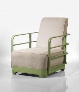 Armchair with ivory-colored upholstery and thin green metal railings for arms.