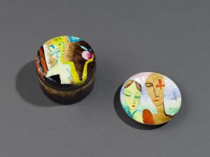 Small, lidded box and dish decorated with abstracted faces of women and colorful geometric forms.