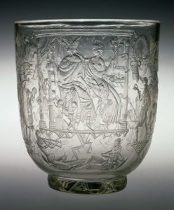 Transparent glass vase decorated with images of a king and queen in a desert setting.