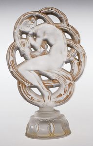 Semitranslucent perfume bottle with a large ornamental stopper, depicting a woman in fetal position against a knot of curving lines.