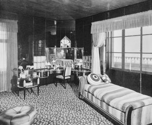 A black and white archival photograph of Elaine’s bedroom depicting her dressing table, daybed, and an assortment of small decorative objects.