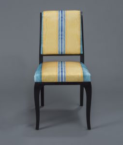 A chair in striped blue and yellow upholstery with a black frame.