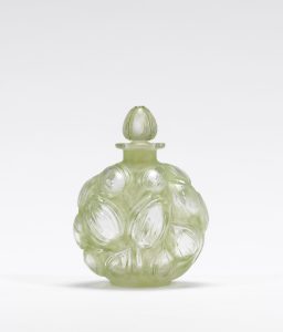 Pale green glass bottle with three-dimensional tulips cut on its surface. Stopper is pale green in the shape of a teardrop.