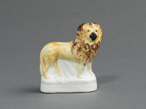 Lion with a mane standing on a white base.