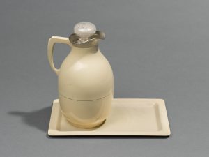 A light yellow carafe, with circular white stopper, and rectangular tray.