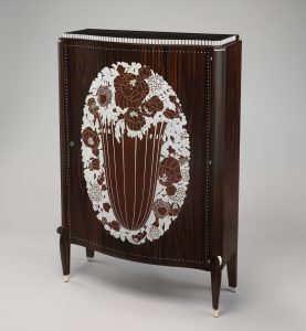 Rounded cabinet in dark, shimmering wood with a white geometric floral motif in the center.