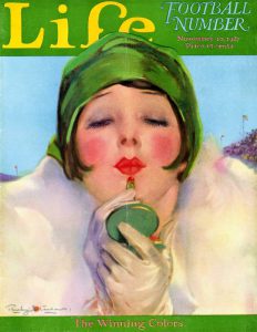 Color drawing of a young woman with bobbed hair under a green cloche hat looking into a compact mirror as she re-applies red lipstick. The word “Life” is printed above her head in yellow on a green background.