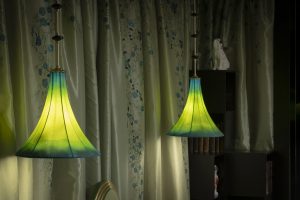 A pair of hanging lamps with fluted, green and blue trumpet-shaped shades.