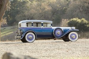Color photograph of a 1930 Ruxton automobile that sits low and has an elongated front, painted in horizontal stripes of (from top to bottom) purple, blue, grey, and black.