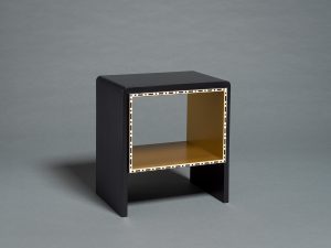 Glossy black table with a hollow center, containing a shelf, and white detailing around the edges.