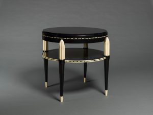 A round, shiny black table with two levels, detailed with ivory-colored plastic.
