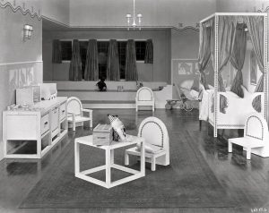 A nursery room featuring geometric white furniture with sparse black detailing.