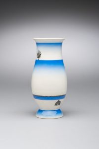 Small white vase decorated with bands of bright blue in an ombré pattern.