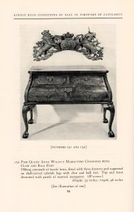 A wooden cabinet with clawed feet, seated beneath an elaborate royal coat of arms.