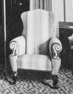 Elaine Wormser’s cushy, curved striped armchair, with large white spirals on the front of its arms, as seen in a black and white photograph of her room.
