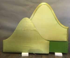 Two identical curved headboard inserts upholstered in pale green silk.