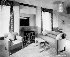 Black and white photo of an interior with a modern-looking armchair, couch, and small table.