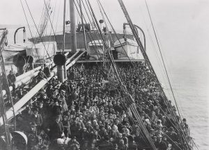 Black and white photo from 1906 of a large ship deck crowded with people.